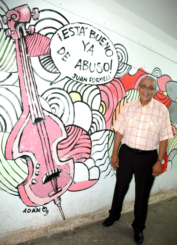 Juan Formell, director de Los Van Van Junto a mural humorístico en el Pabellón Cuba. Con motivo del día de la Cultura Cubana en el año 2009